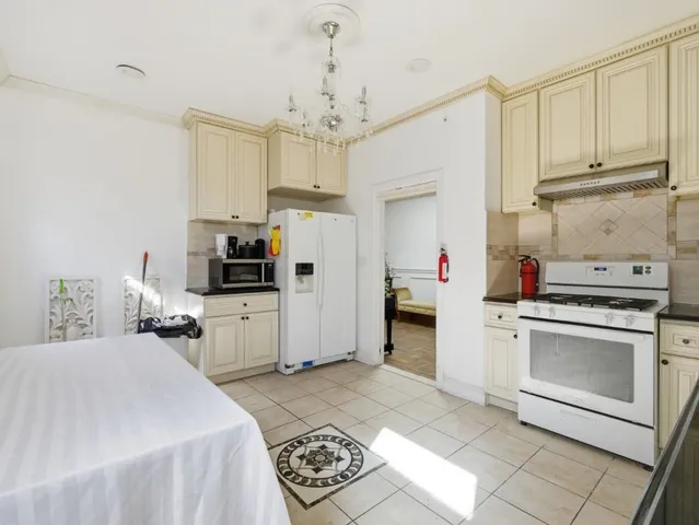 a kitchen with stainless steel appliances kitchen island granite countertop a refrigerator sink and white cabinets