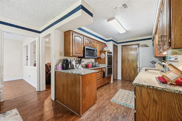 a view of kitchen with stainless steel appliances granite countertop lots of counter top space