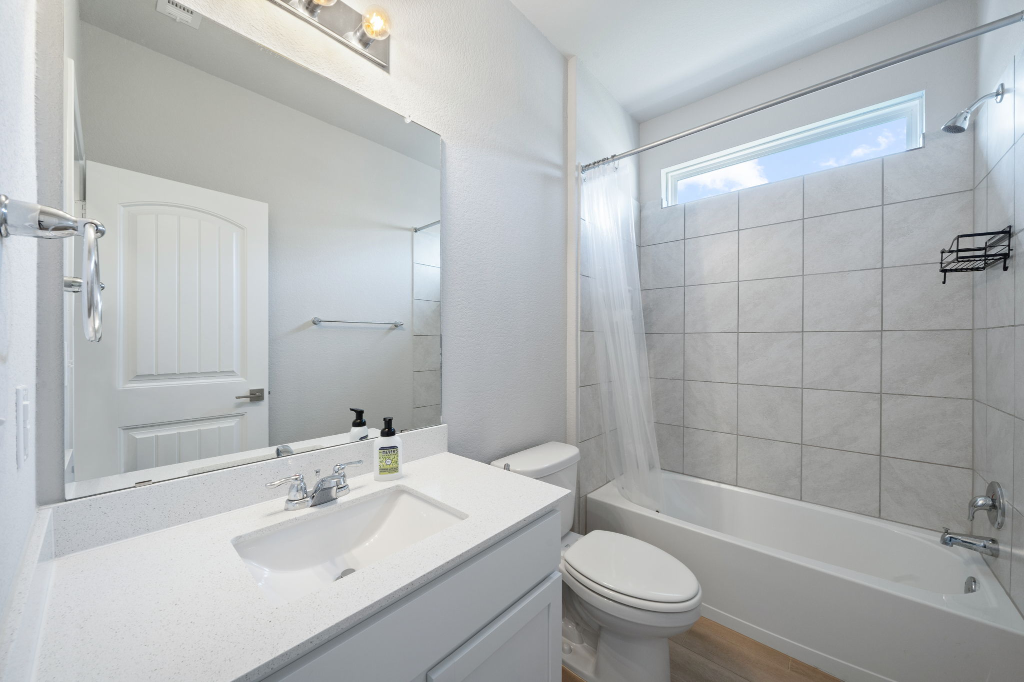 2412 Starhill Ranch Street Georgetown, TX 78628 - Photo 7 of 40 A well-appointed bath features a sleek vanity and a tiled shower with a transom window.