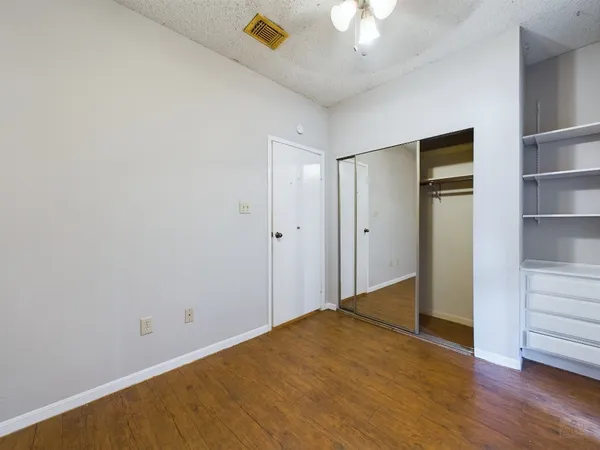 a view of empty room with wooden floor and ceiling fan