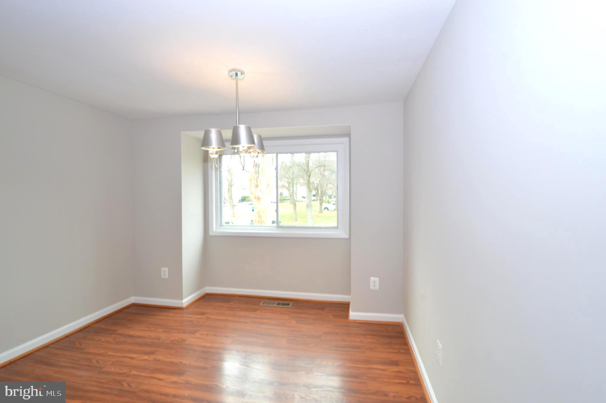 9410 Merryrest Road Columbia, MD 21045 - Photo 8 of 26 an empty room with wooden floor chandelier and window