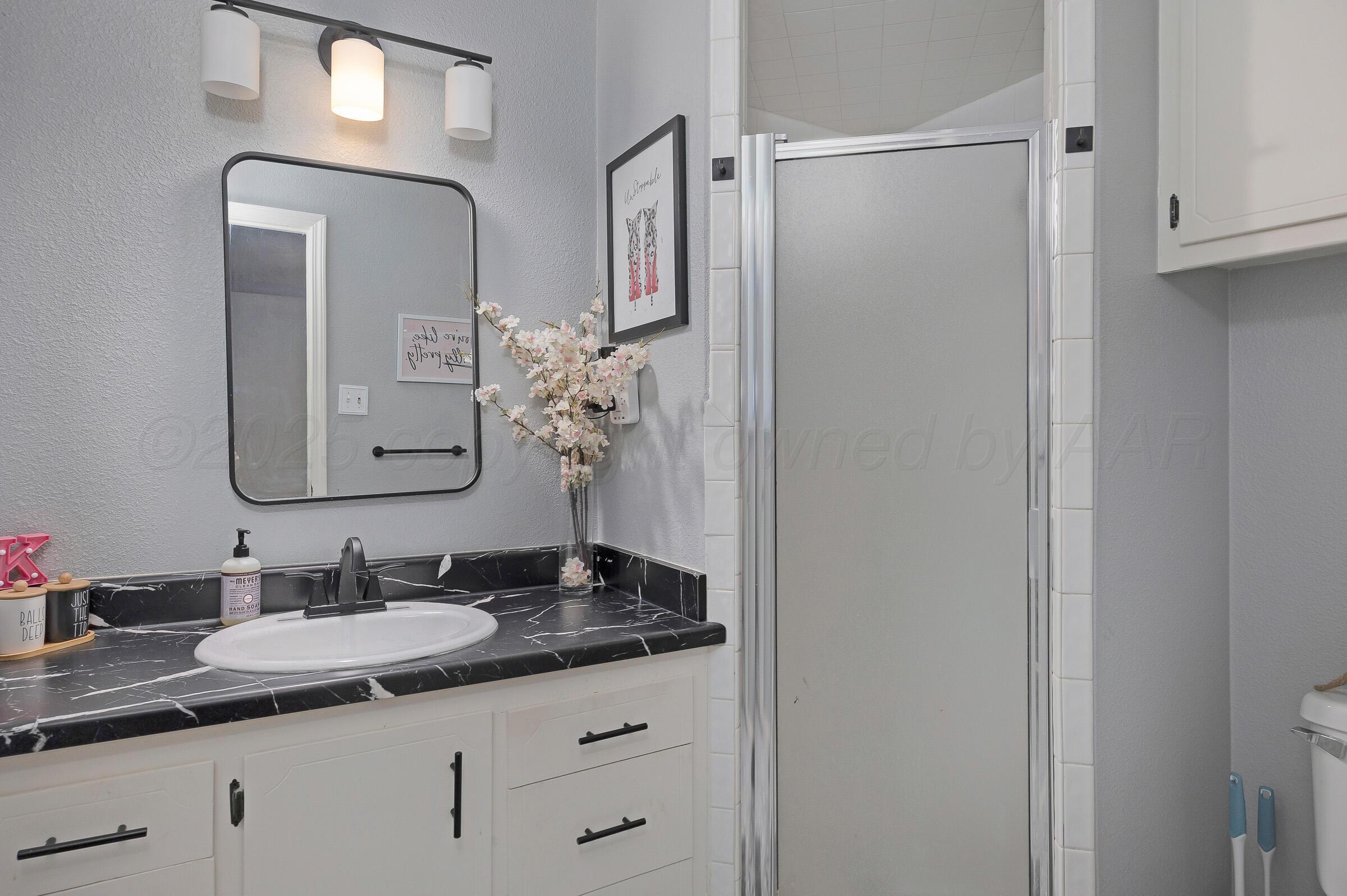 4020 Tulane Drive Amarillo, TX 79109 - Photo 15 of 23 a bathroom with a granite countertop sink a mirror and shower