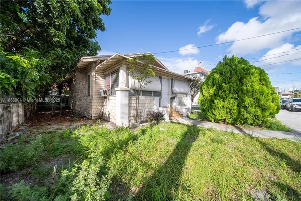 a view of a house with a small yard plants and large tree