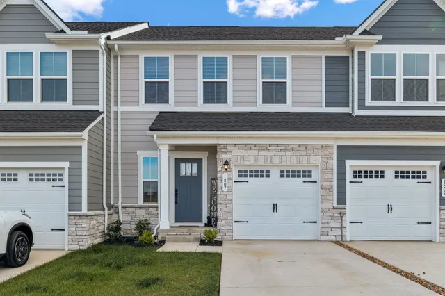 a front view of a building with a garden and parking space