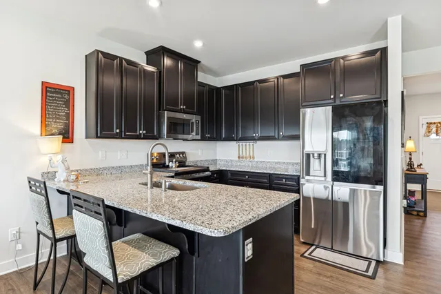 a kitchen with granite countertop stainless steel appliances a sink stove and refrigerator
