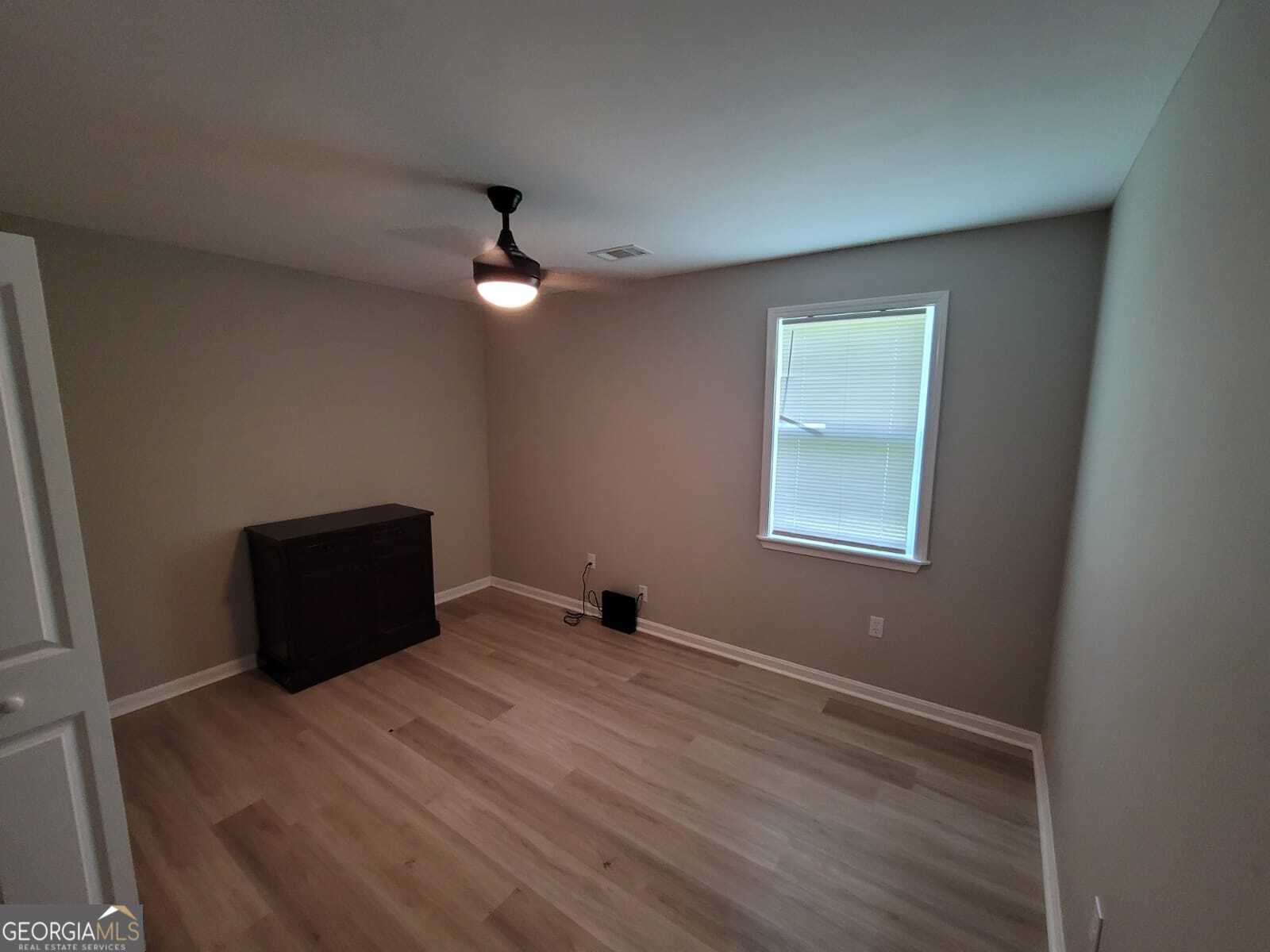 1559 Alma Street Southwest Atlanta, GA 30311 - Photo 4 of 7 an empty room with wooden floor ceiling fan and window