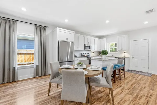 a kitchen with a table chairs refrigerator and microwave