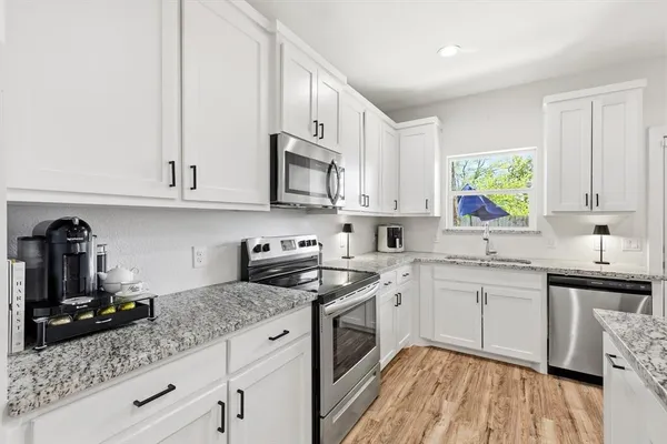 a kitchen with stainless steel appliances granite countertop white cabinets a sink and dishwasher