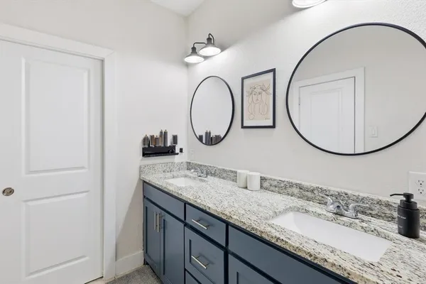 a bathroom with a granite countertop double vanity sink and a mirror