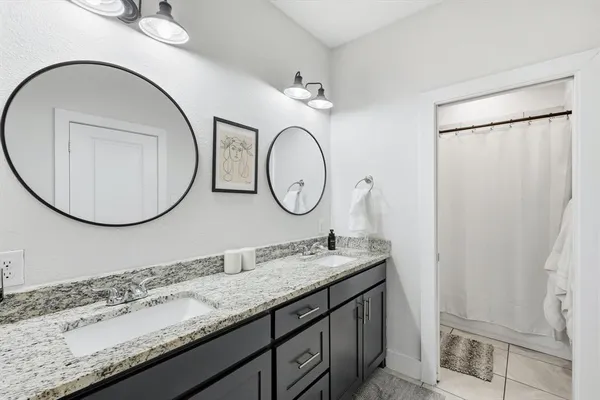 a bathroom with a granite countertop double vanity sink and a mirror