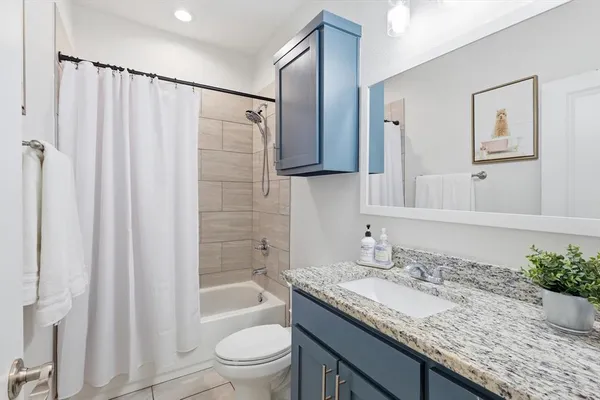 a bathroom with a granite countertop sink a toilet and shower