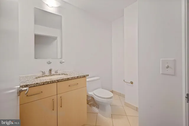a bathroom with a granite countertop sink a toilet and a mirror