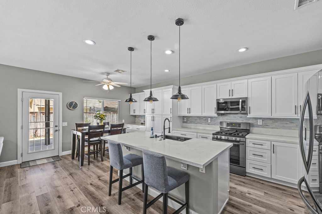 1251 Stepstone Court Hemet, CA 92545 - Photo 16 of 51 a kitchen with stainless steel appliances kitchen island granite countertop a stove a sink a dining table and chairs with wooden floor