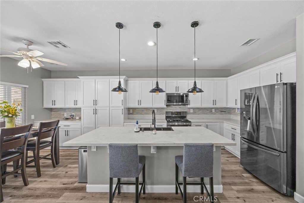 1251 Stepstone Court Hemet, CA 92545 - Photo 6 of 51 a kitchen with stainless steel appliances kitchen island granite countertop a dining table chairs and a refrigerator