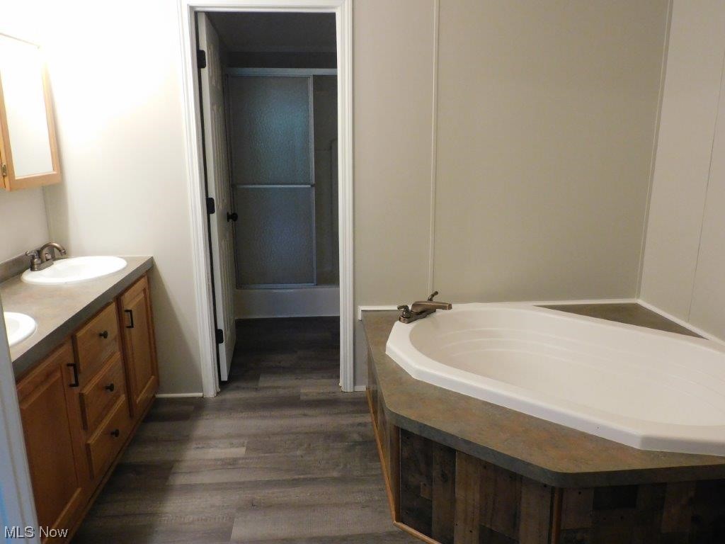 6045 Gore Road Ashtabula, OH 44004 - Photo 16 of 23 Master Bathroom view A with a bathing tub, double sink vanity, and wood-type flooring