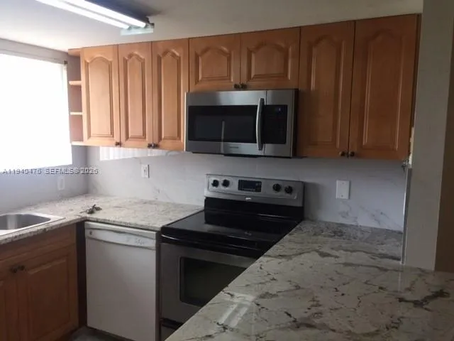 a kitchen with stainless steel appliances granite countertop a sink stove and refrigerator