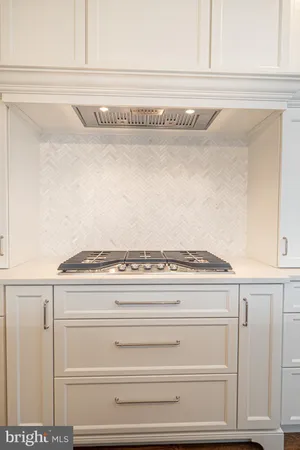 a large white kitchen with a stove a refrigerator a oven and wooden floor