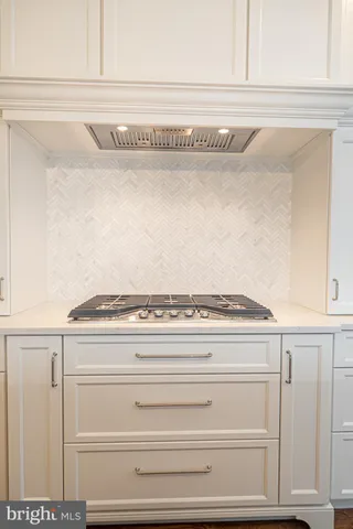 a large white kitchen with a stove a refrigerator a oven and wooden floor