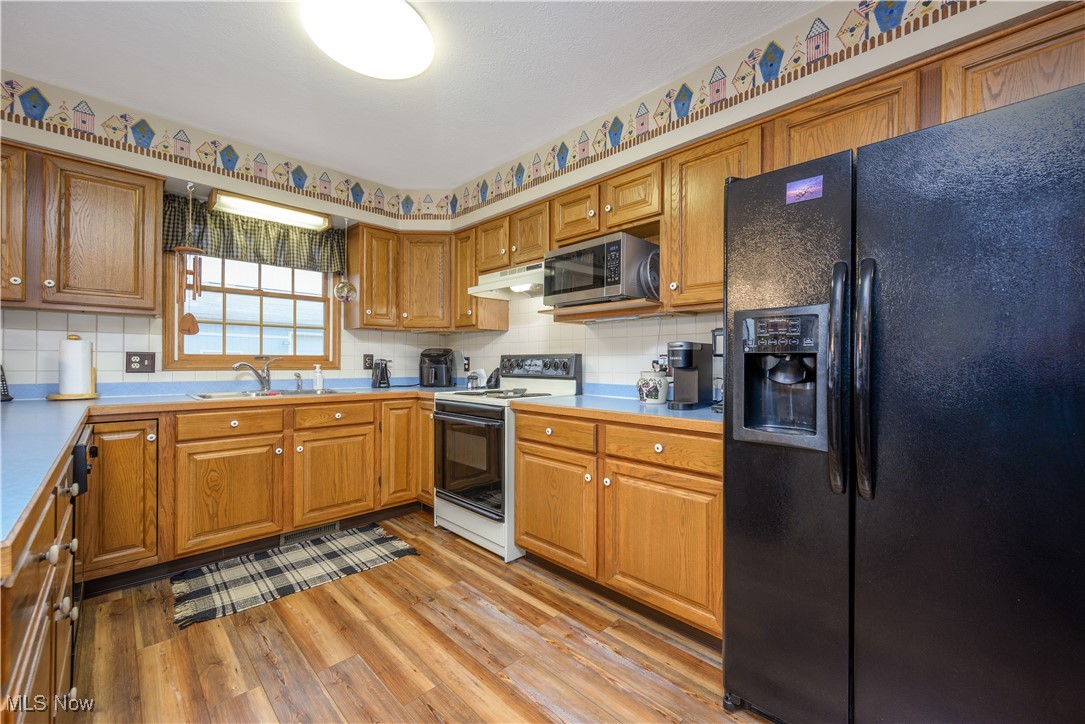 893 Industry Road Atwater, OH 44201 - Photo 17 of 50 Kitchen with backsplash, black refrigerator with ice dispenser, sink, light hardwood / wood-style flooring, and white electric stove