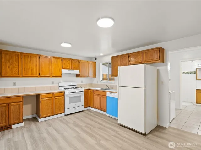 a kitchen with a refrigerator a stove top oven a sink dishwasher and wooden cabinets