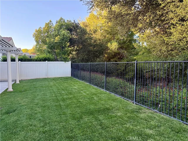 a view of a backyard with a tree and wooden fence