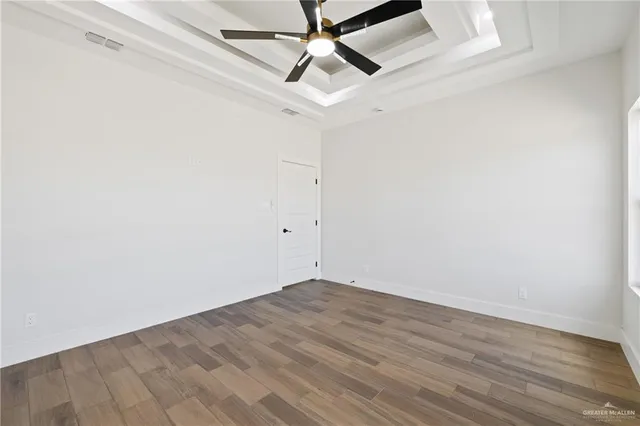an empty room with a ceiling fan and wooden floor