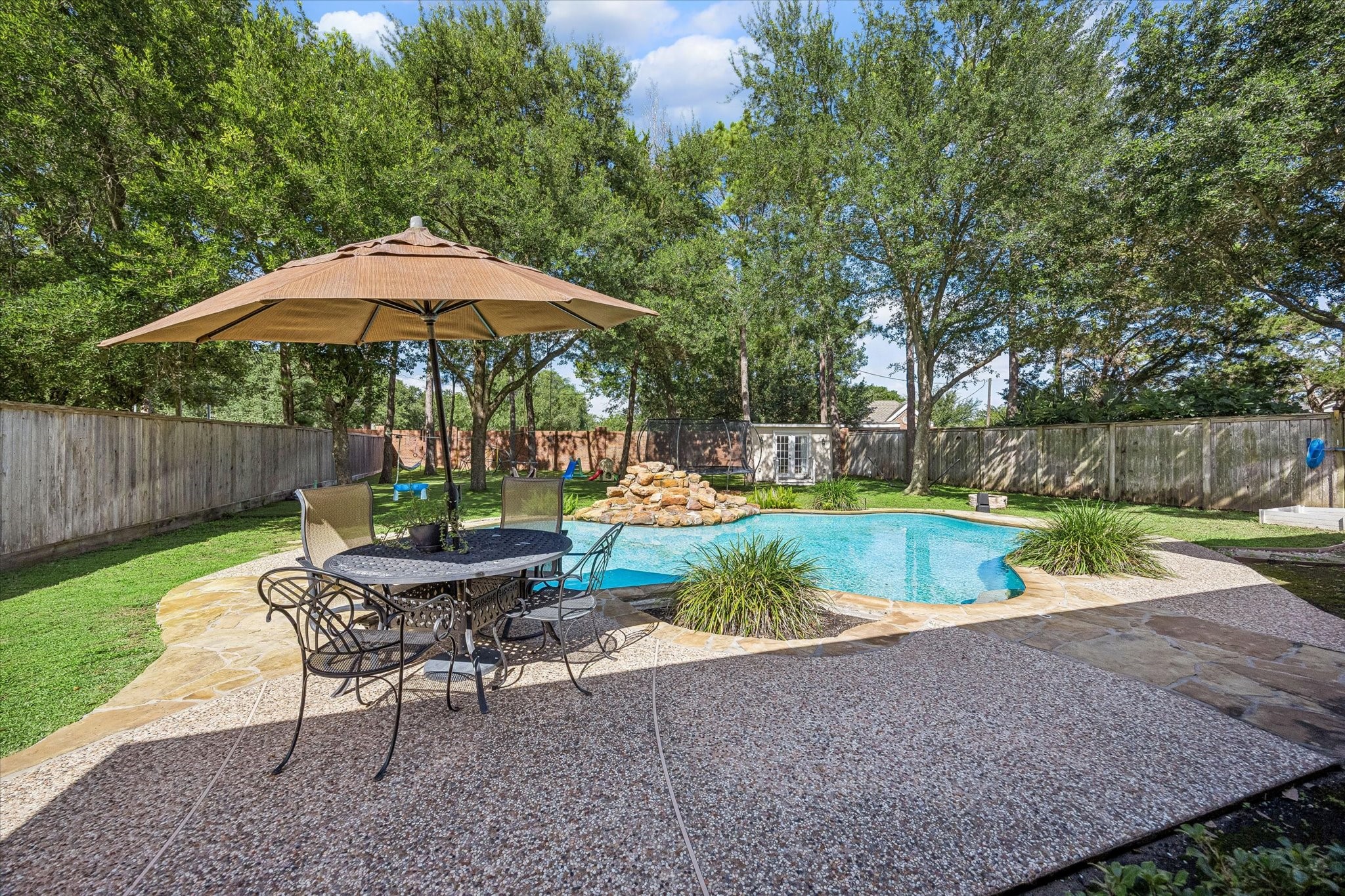 3047 Bonnebridge Way Boulevard Houston, TX 77082 - Photo 20 of 50 Resort-inspired backyard retreat featuring a sparkling pool, expansive decking, and lush mature landscaping, creating a picturesque setting for outdoor living. Thoughtfully designed for both relaxation and entertaining, the private outdoor oasis offers the perfect balance of comfort, tranquility, and year-round enjoyment.