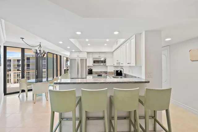 a kitchen with stainless steel appliances granite countertop a table and chairs in it