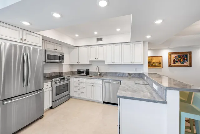 a kitchen with granite countertop stainless steel appliances and refrigerator