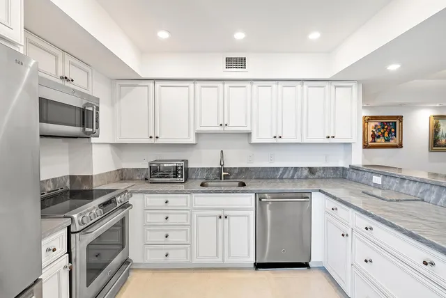 a kitchen with granite countertop white cabinets white stainless steel appliances with a sink and dishwasher
