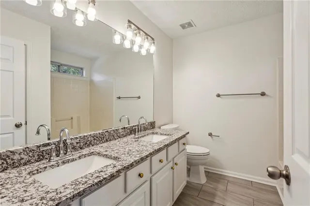 a bathroom with a granite countertop sink a toilet and a mirror