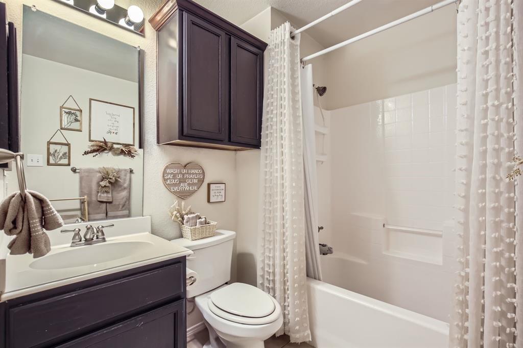 504 Thunder Trail Forney, TX 75126 - Photo 16 of 23 Bathroom featuring a dark wood vanity with a white sink, a matching dark wood storage cabinet, and a white bathtub with a shower
