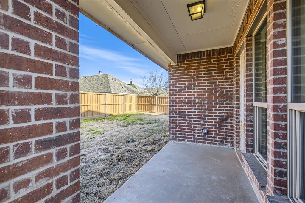 504 Thunder Trail Forney, TX 75126 - Photo 21 of 23 The property features an outdoor patio area with a concrete surface, brick exterior walls, and a recessed ceiling light fixture