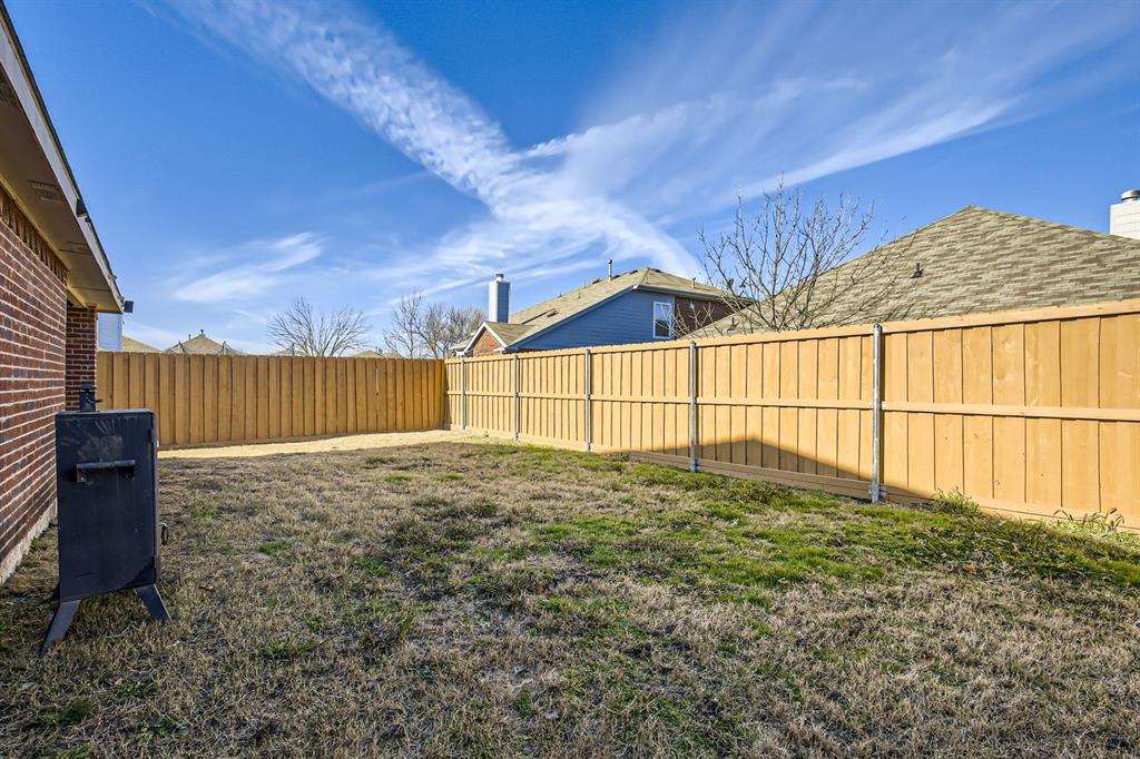 504 Thunder Trail Forney, TX 75126 - Photo 22 of 23 The property features an outdoor area with a wooden fence and a brick exterior wall