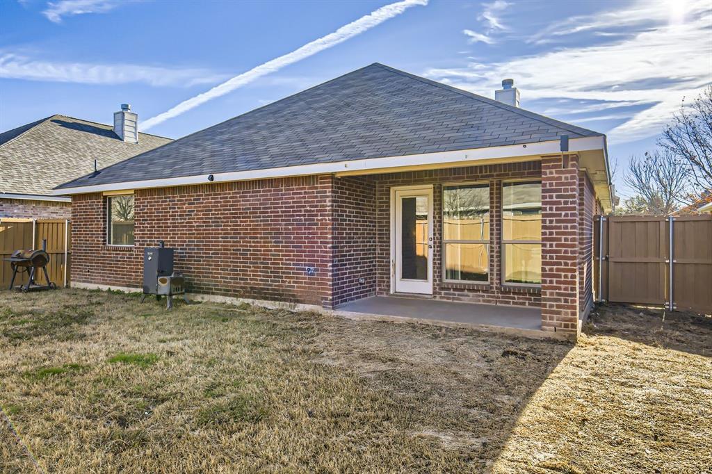 504 Thunder Trail Forney, TX 75126 - Photo 23 of 23 The property features a brick exterior, a covered patio area, and a private fenced yard