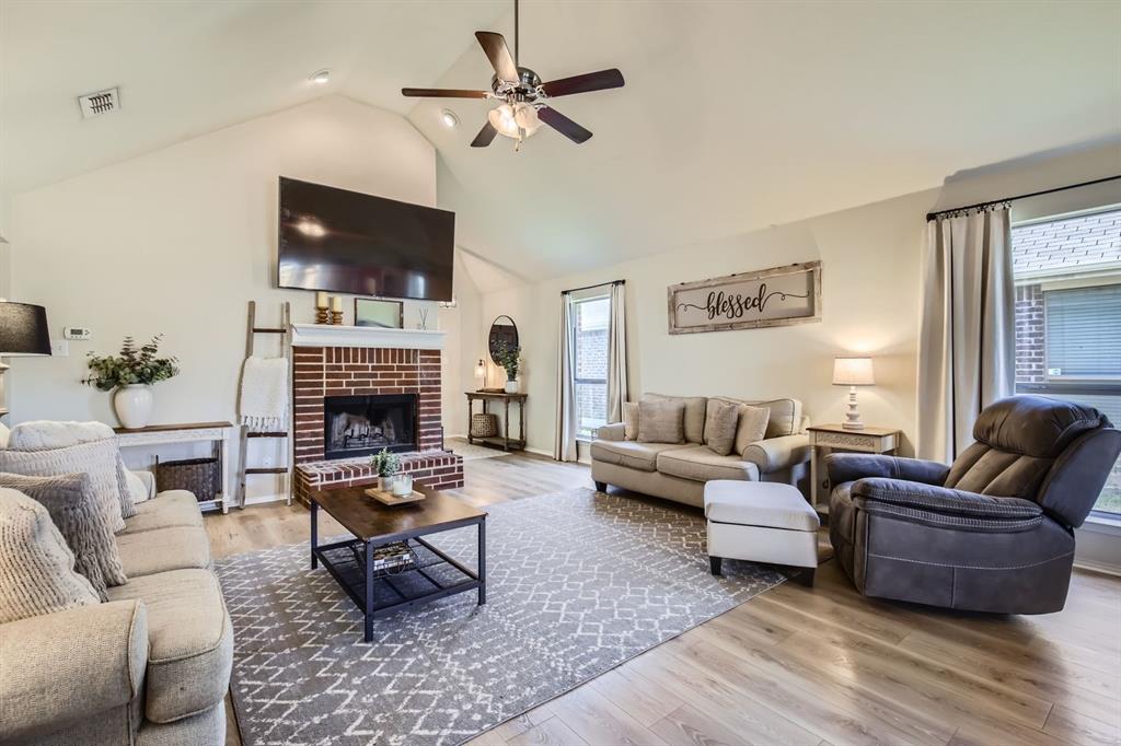 504 Thunder Trail Forney, TX 75126 - Photo 4 of 23 The living room features vaulted ceilings, light wood-style flooring, and a brick fireplace