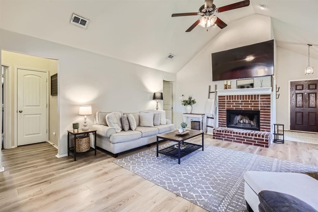 504 Thunder Trail Forney, TX 75126 - Photo 5 of 23 This living area features a brick fireplace, a vaulted ceiling, and light-toned flooring