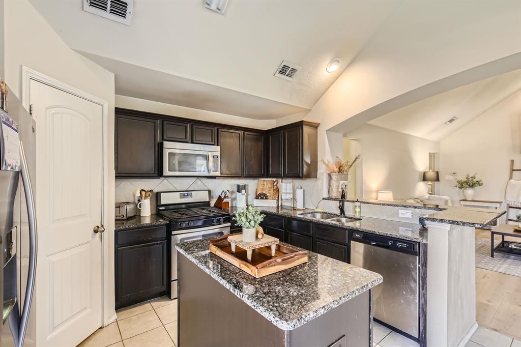 504 Thunder Trail Forney, TX 75126 - Photo 8 of 23 The kitchen features dark cabinetry, granite countertops, and stainless steel appliances, including a microwave, gas range, and dishwasher