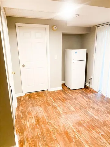 a view of empty room with wooden floor and door