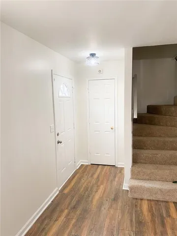 a view of an empty room with stairs and wooden floor