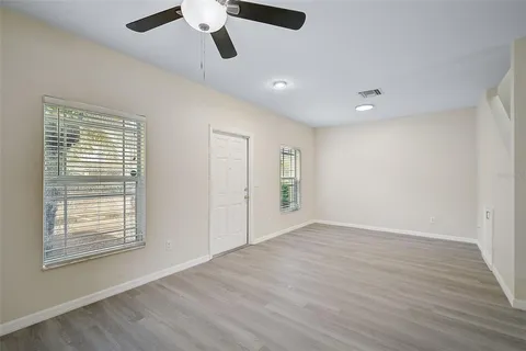 a view of an empty room with wooden floor and a window