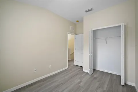 a view of an empty room with wooden floor and closet