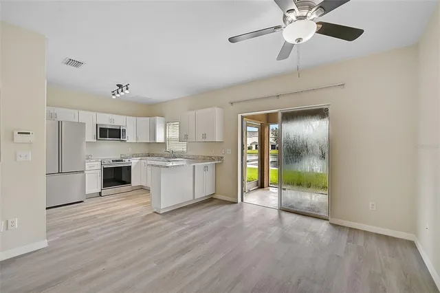 a view of a kitchen with wooden floor and a ceiling fan