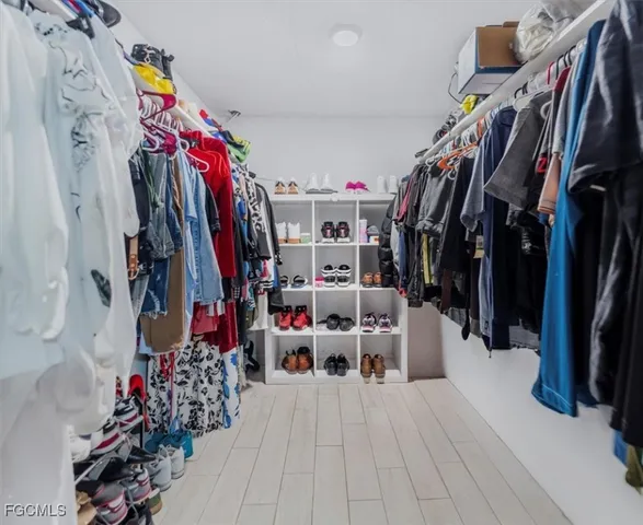 a view of walk in closet with clothes and shoes