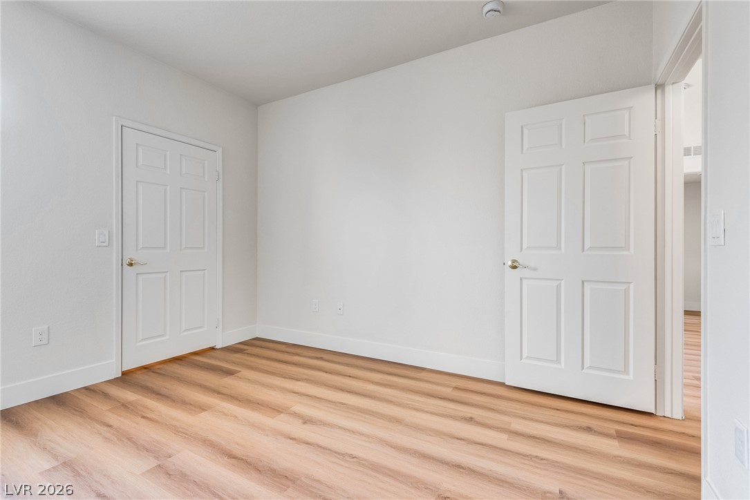 10550 West Alexander Road, Unit 2174 Las Vegas, NV 89129 - Photo 25 of 28 Smooth wood-plank flooring and crisp white trim enhance this versatile bedroom space.