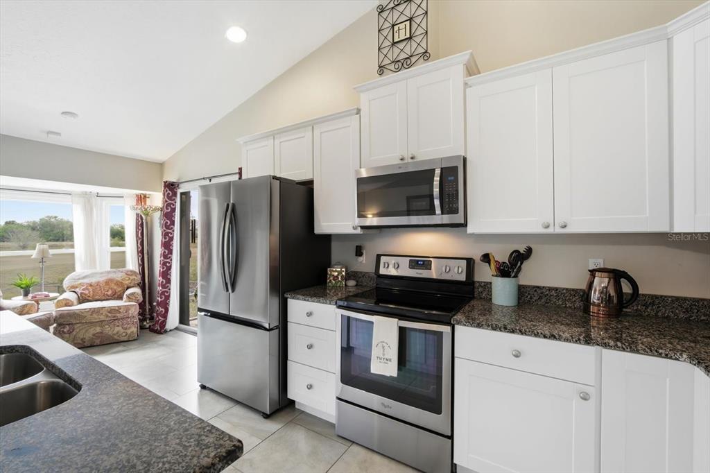 846 Birdie Way Apollo Beach, FL 33572 - Photo 11 of 31 a kitchen with stainless steel appliances granite countertop a refrigerator a stove a sink and white cabinets with wooden floor
