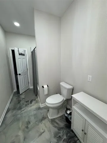 a white toilet sitting next to a bathroom sink and a mirror