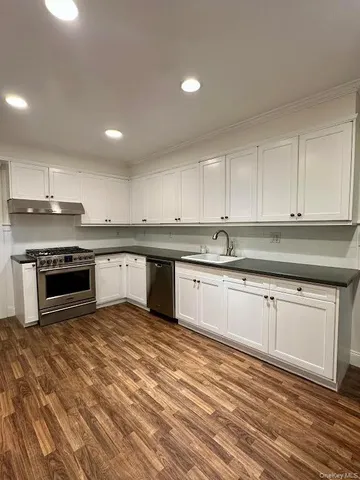 a large kitchen with granite countertop a stove top oven sink and cabinets