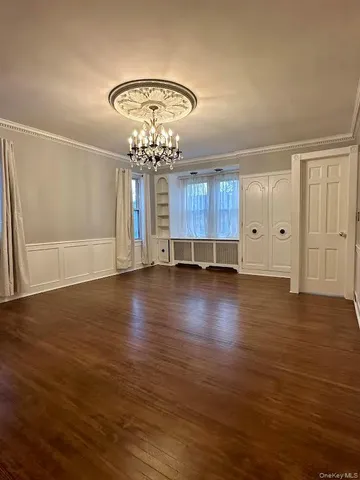 an empty room with wooden floor and chandelier