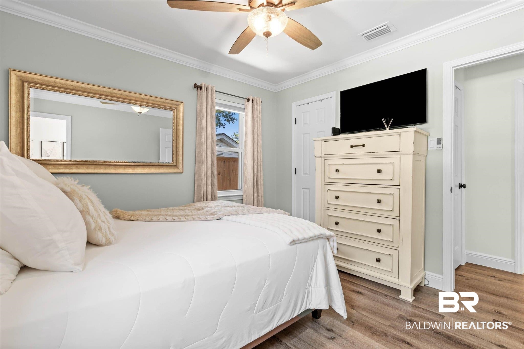 101 Ann Street Daphne, AL 36527 - Photo 16 of 38 Bedroom featuring wood-finish flooring, a ceiling fan with integrated lighting, crown molding, and painted baseboards